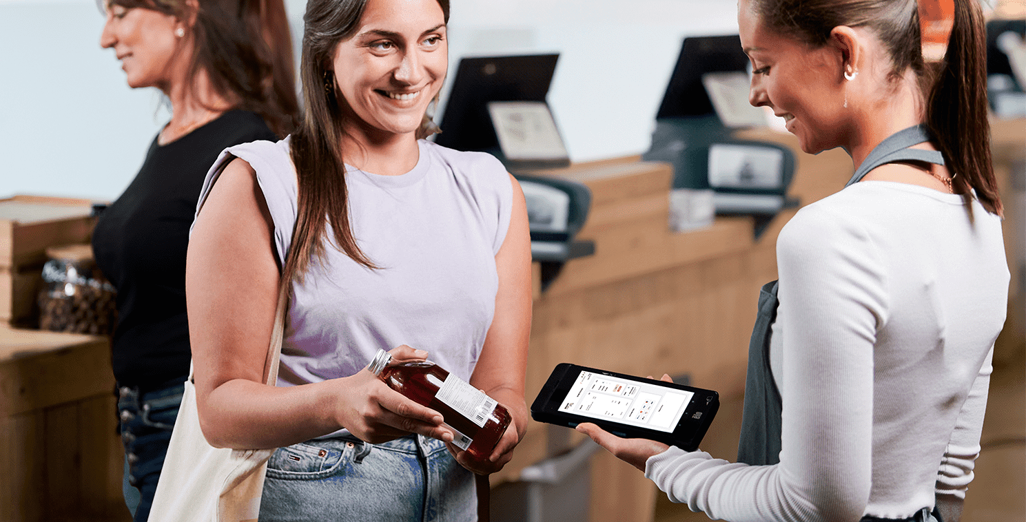 Zwei Käufer nutzen ein großes Touchdisplay in einem Geschäft, um virtuelle Bekleidungsoptionen zu erkunden – ein Beispiel für erlebnisorientierte Einzelhandelstechnologie und personalisierte Kundenansprache vor Ort.